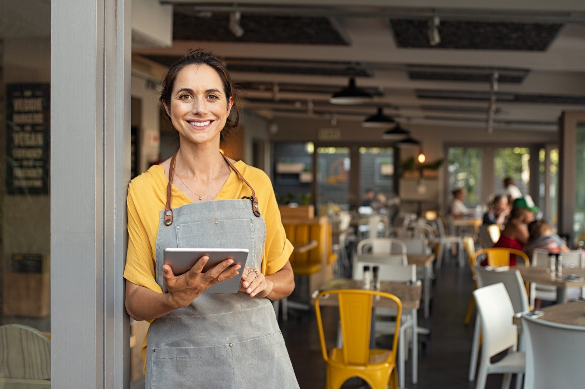 Claims Smiling cafe owner holding a tablet in her restaurant