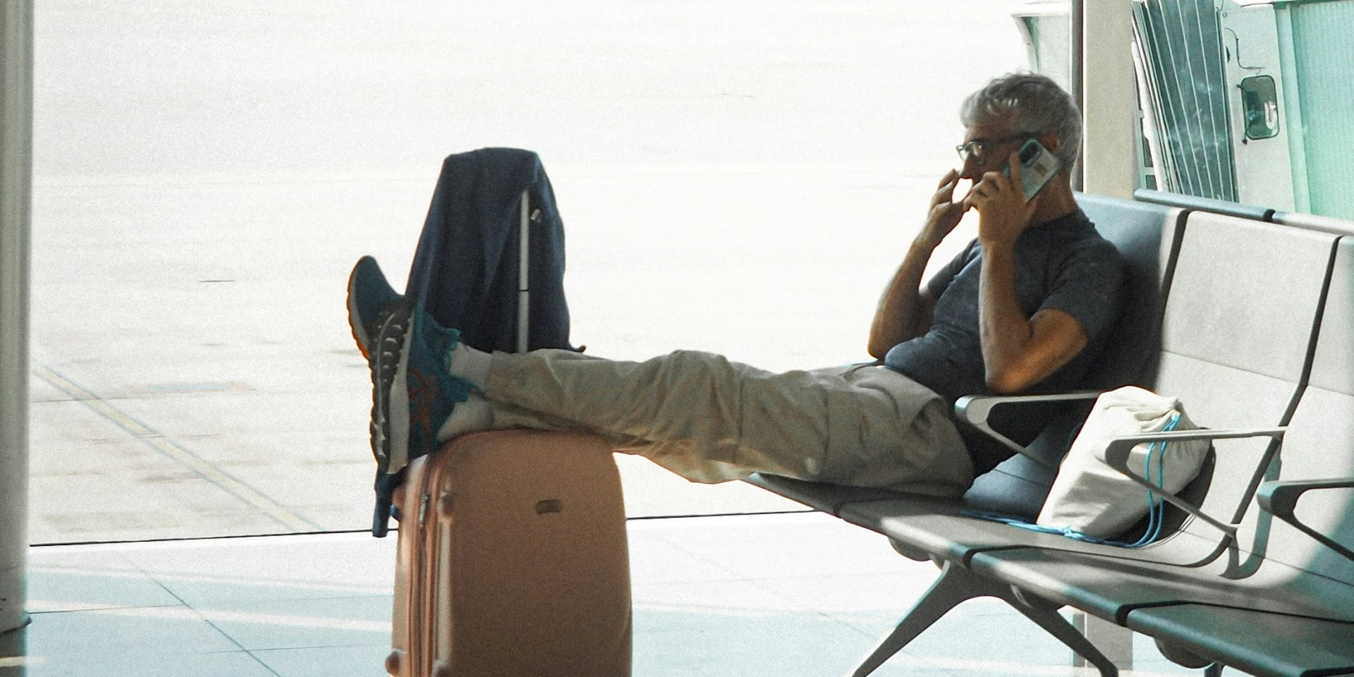 People Risks Traveller resting beside a suitcase at an airport window